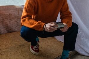 boy in orange sweater and blue pants sitting on brown couch