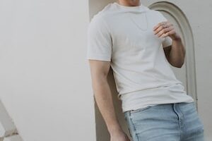 man in white crew neck t-shirt and blue denim jeans standing beside white wall