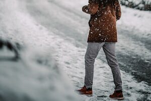 person in brown jacket and white pants holding umbrella