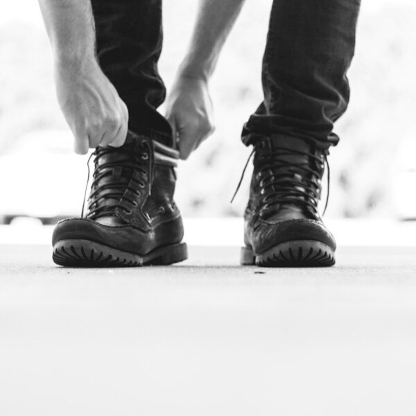 person wearing black leather lace-up boots