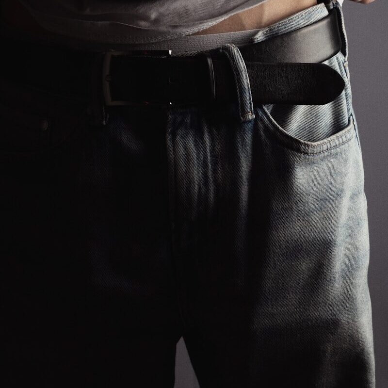a man is wearing a belt and jeans
